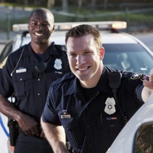Two police officers, standing next to the police car and smiling | St. Louis Police Department is hiring a full-time police officer.