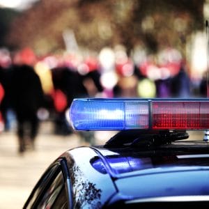 Crowd of people and the siren on top of a police car | COVID-19