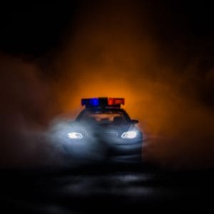 Police vehicle with headlights on in the dark | False Statement