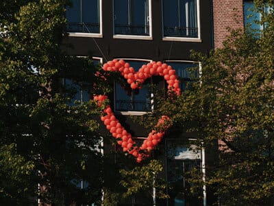 Red balloons in a heart shape on a building | Premium Pay Update