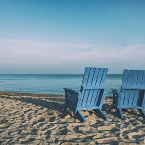 Two empty chair on the beach, facing the ocean. | Retirement With Adult Children | Lifestyle Choices