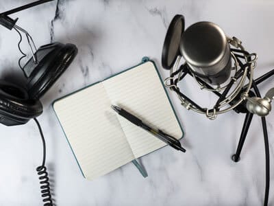 Flat lay of a podcast setting with microphone, headphones and a notebook | Impact on Law Enforcement