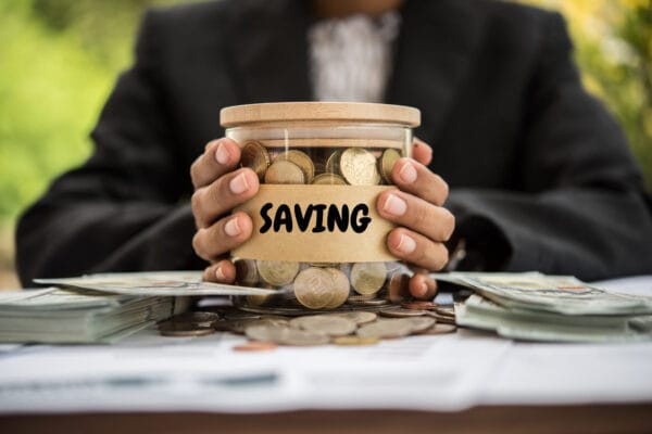 Man holding jar of money for emergency funds.