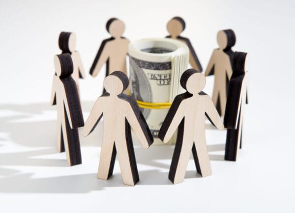 Cardboard figure standing in a cirle with a roll of money inside |Investing for Impact
