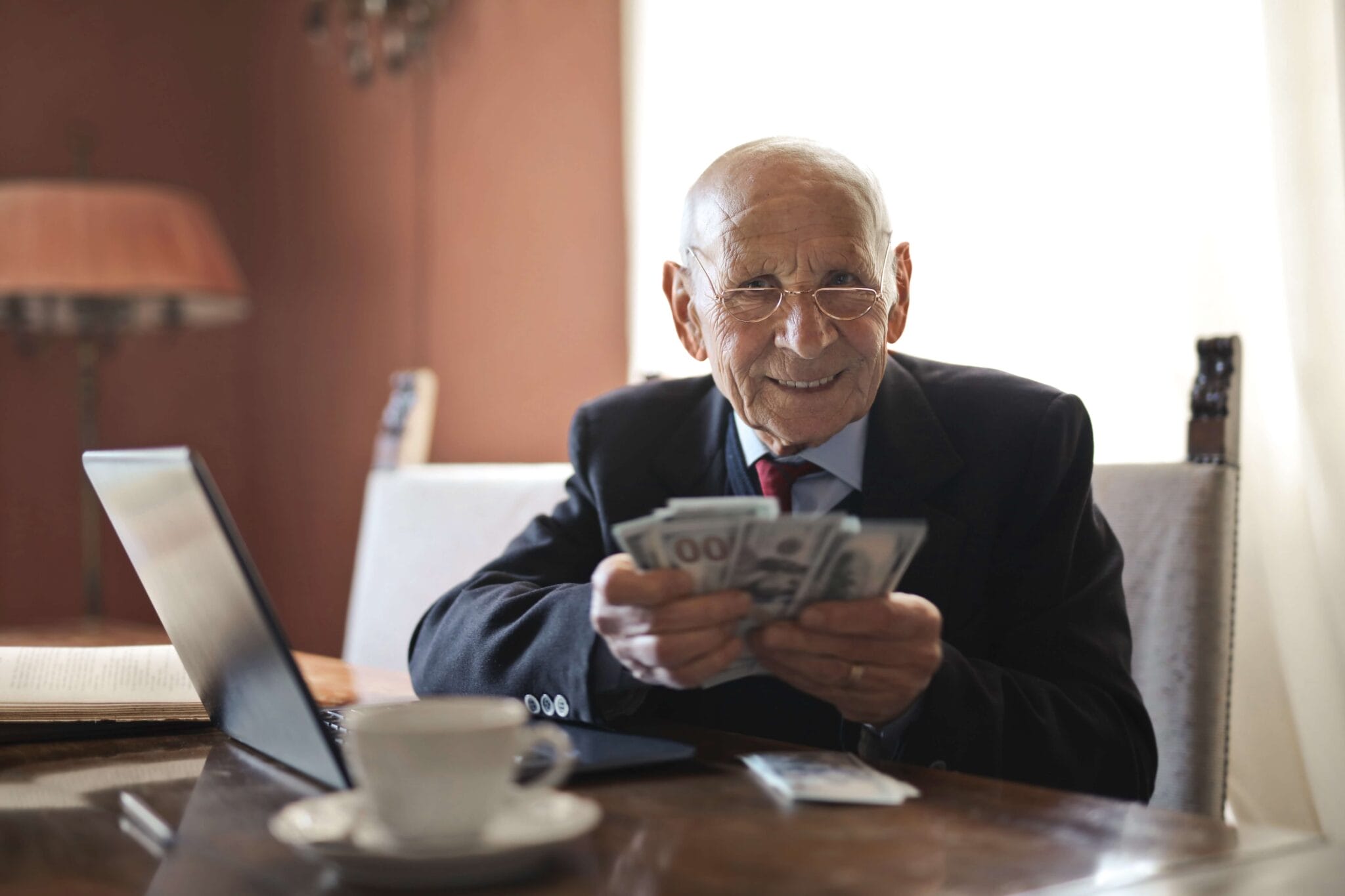 An older gentleman sitting at a desk with money in his hands | Assessing Life Insurance Needs - POAM