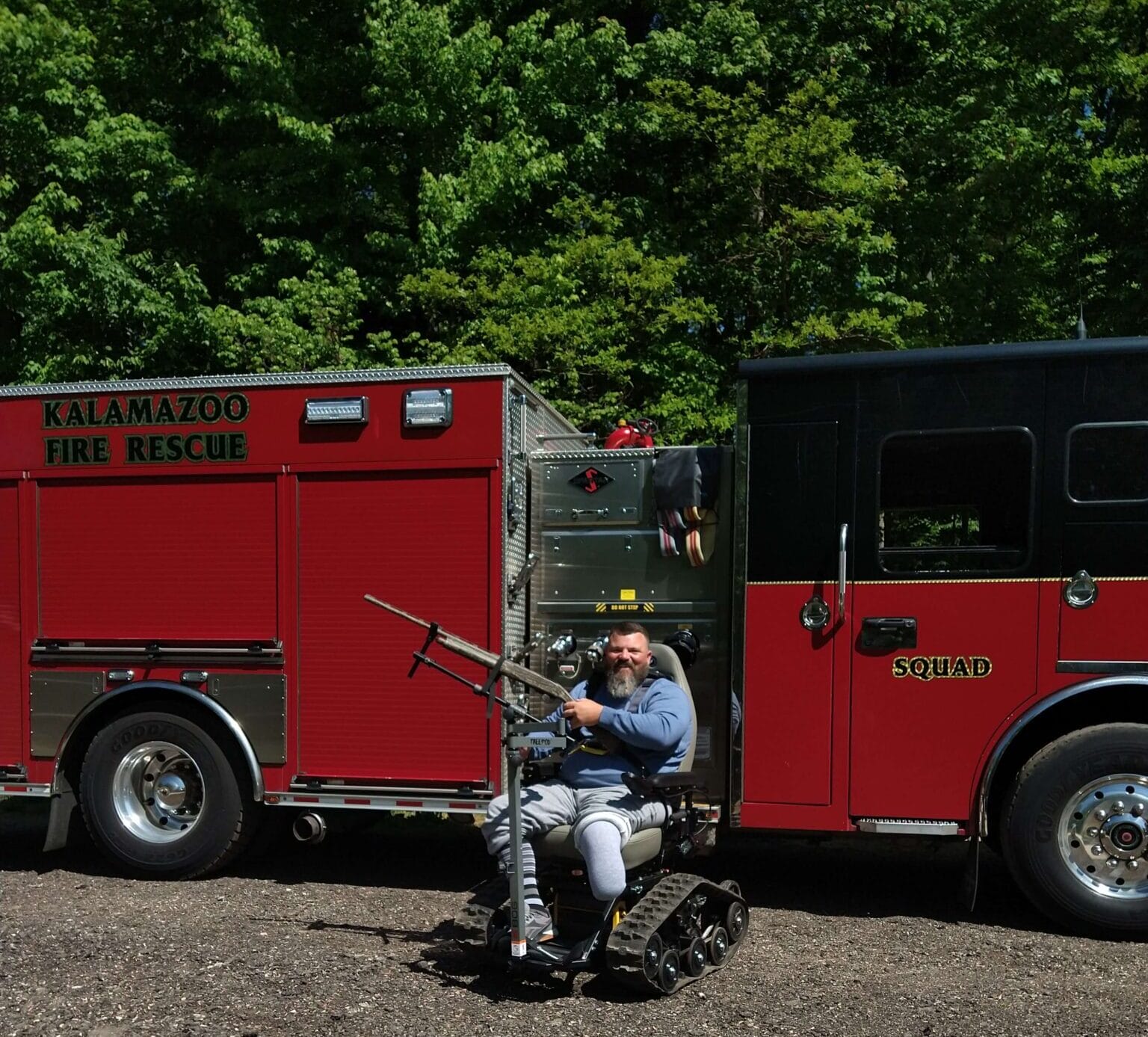Tom Maher posing with gun attachment for TracFab all-terrain wheelchair
