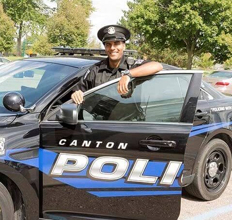 Canton Police Officer posing behind open door of police cruiser | POAM Careers