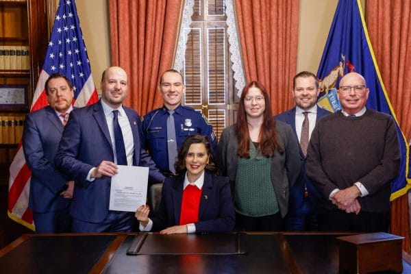 Senator Kevin Hertel, POAM Legislative Director Kenneth E. Grabowski, and others during the ceremonial bill signing with Governor Gretchen Whitmer.