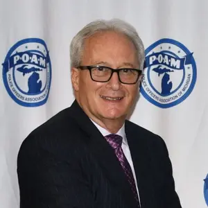 POAM Summer Update - President Tignanelli in front of backdrop