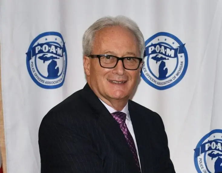 POAM Summer Update - President Tignanelli in front of backdrop
