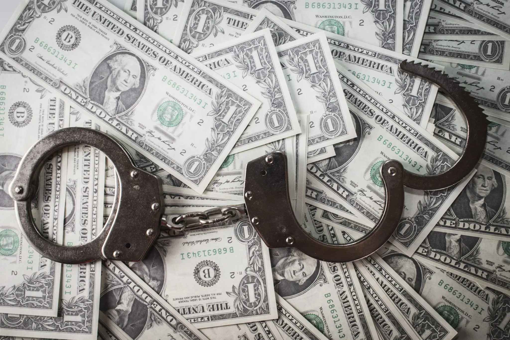 Handcuffs laying on pile of money | Midwest Anti-Illegal Trade